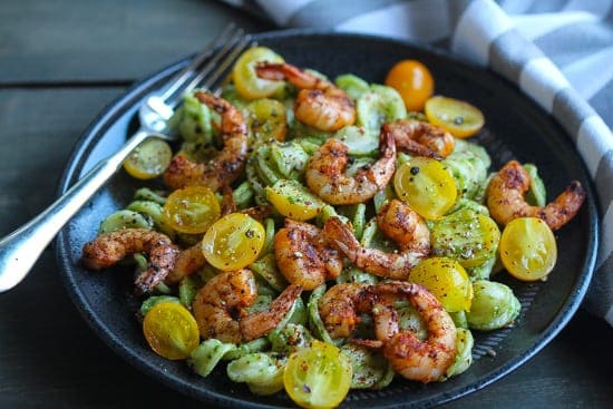 baby kale pesto pasta with spicy shrimp on a plate.