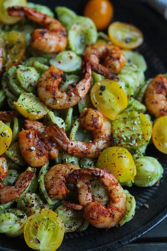 baby kale pesto pasta with spicy shrimp on a plate.