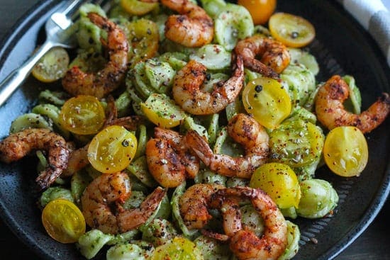 baby kale pesto pasta with spicy shrimp on a plate.