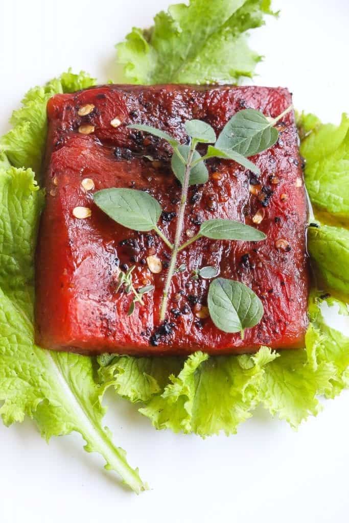 roasted watermelon steak on a plate with greens