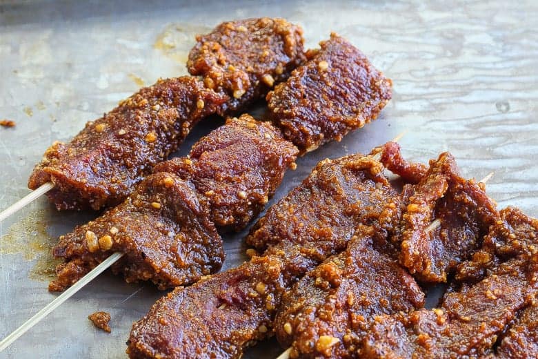 beef suya skewers raw on pan