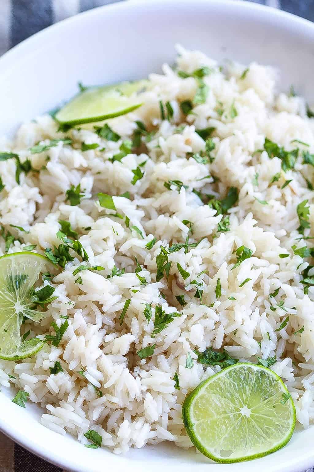 coconut ginger rice in a bowl and topped with limes and cilantro