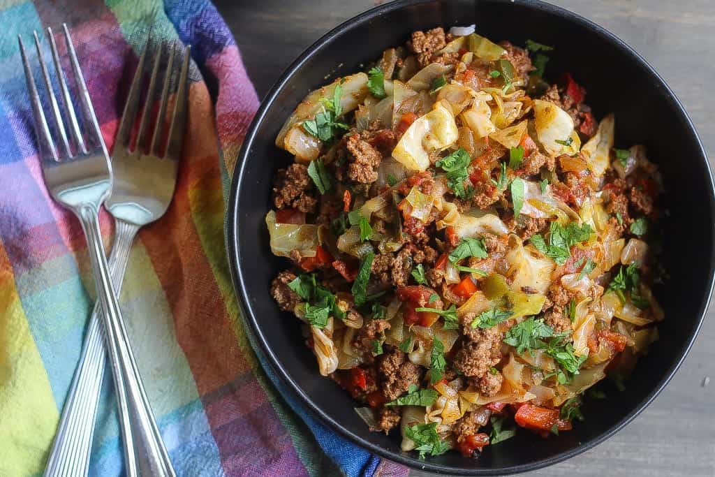 beef and cabbage stir fry in a black bowl