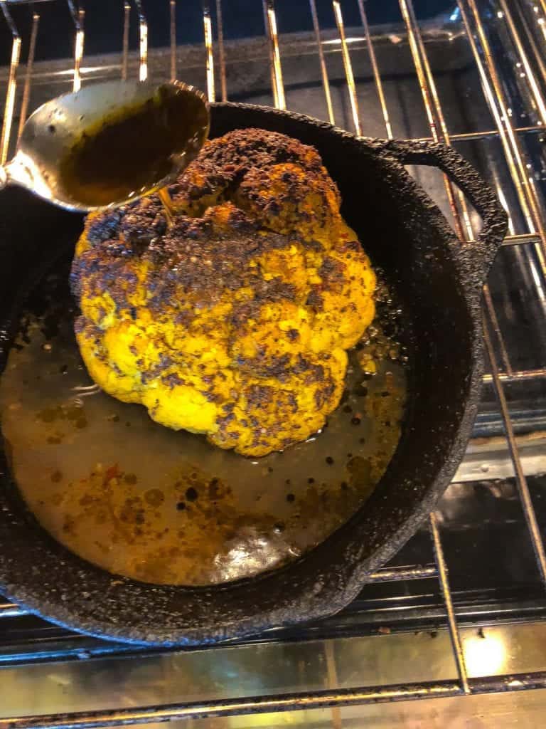 whole roasted jerk cauliflower baking in oven