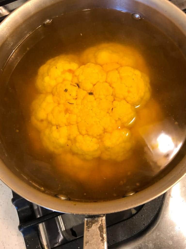 whole yellow cauliflower in poaching liquid