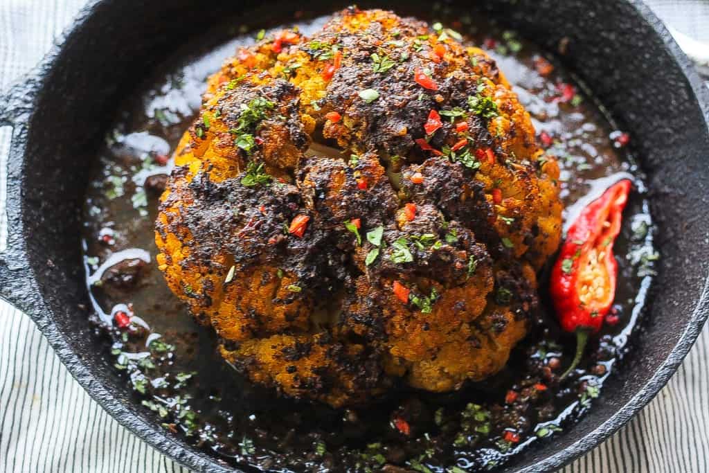 whole roasted jerk cauliflower in a skillet