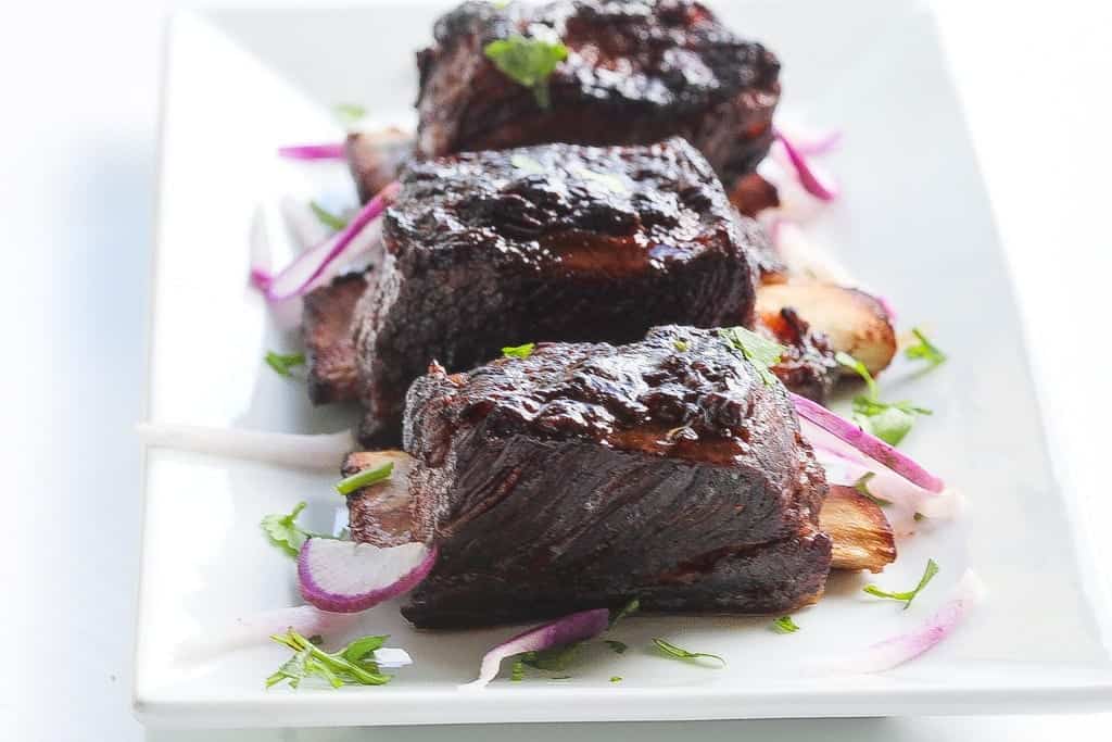 sous vide short ribs glazed and on a plate with purple daikon and cilantro