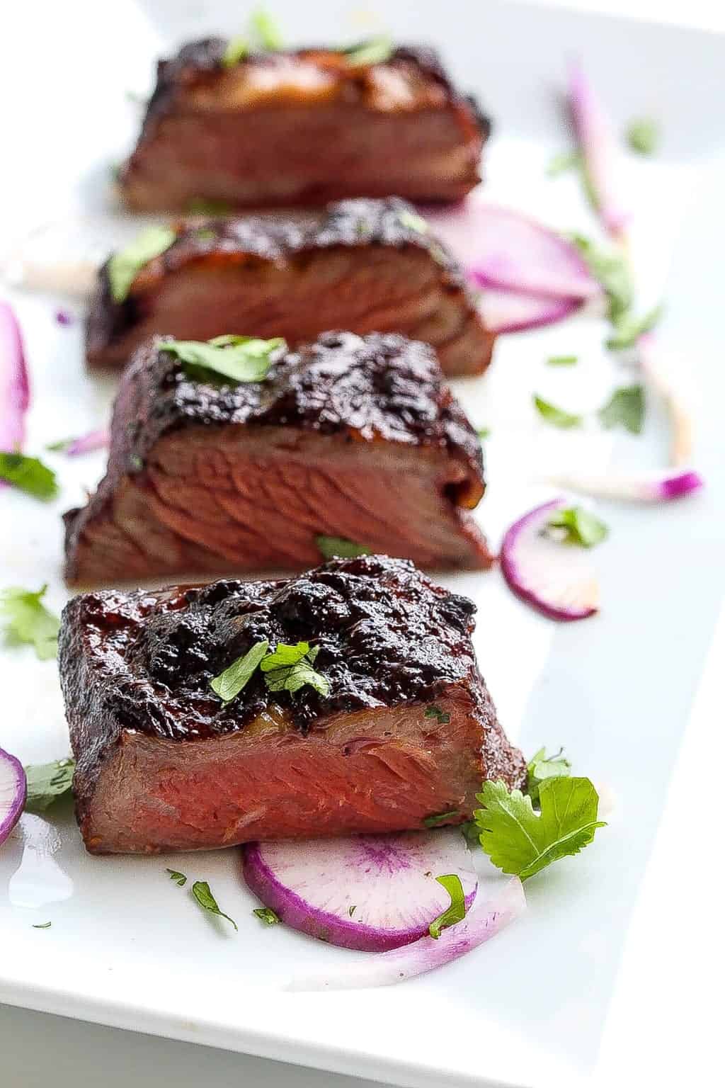 sous vide short ribs glazed and on a plate with purple daikon and cilantro