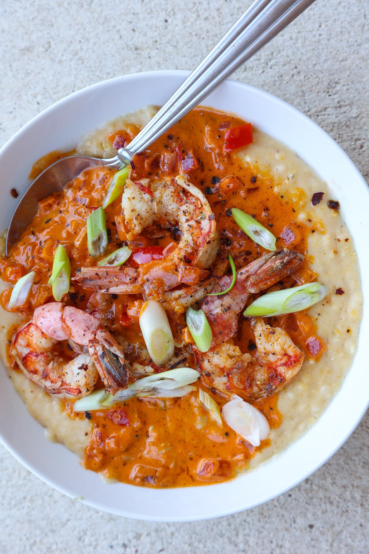 shrimp and grits in a bowl topped with red pepper sauce