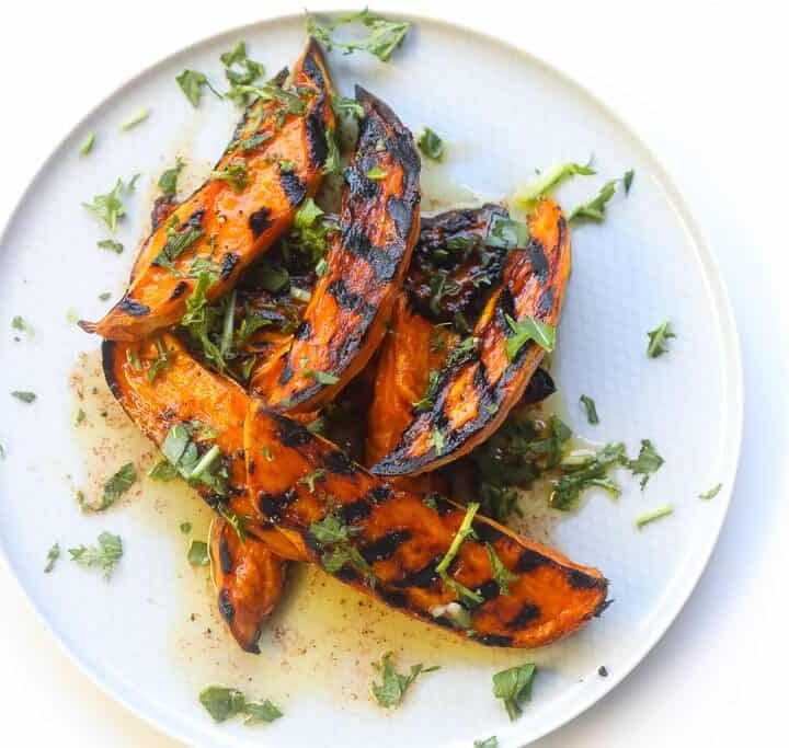 grilled sweet potato wedges on a plate topped with chili lime sauce