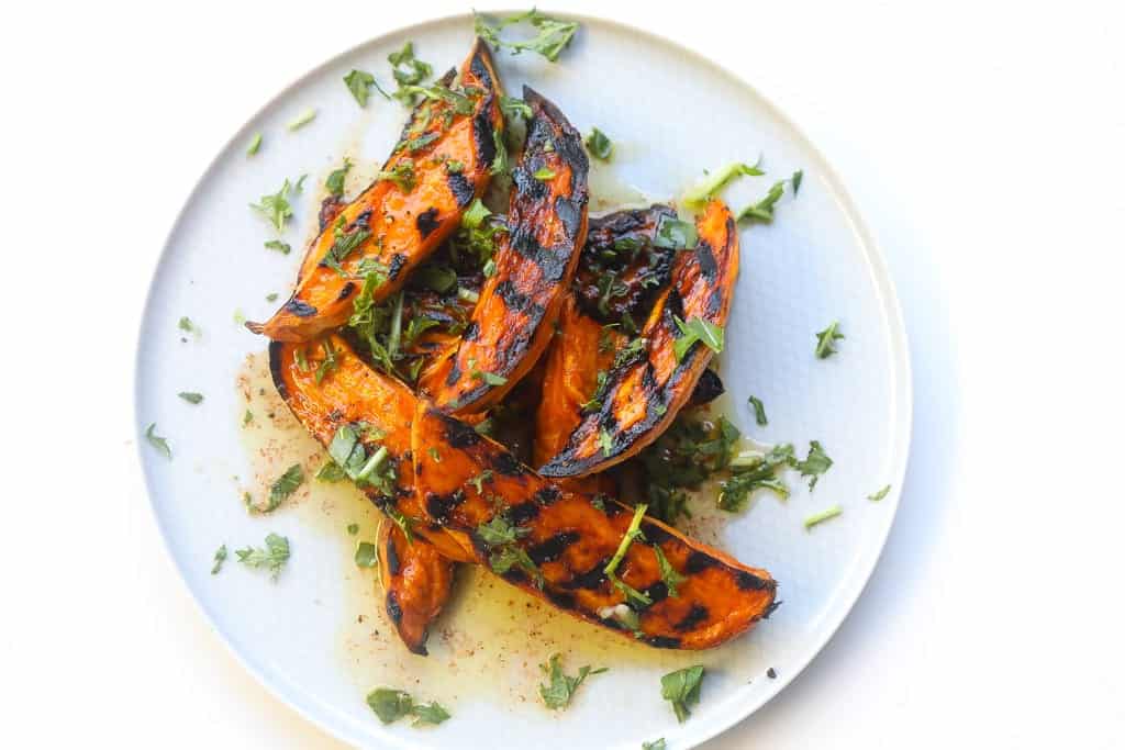grilled sweet potato wedges on a plate topped with chili lime sauce