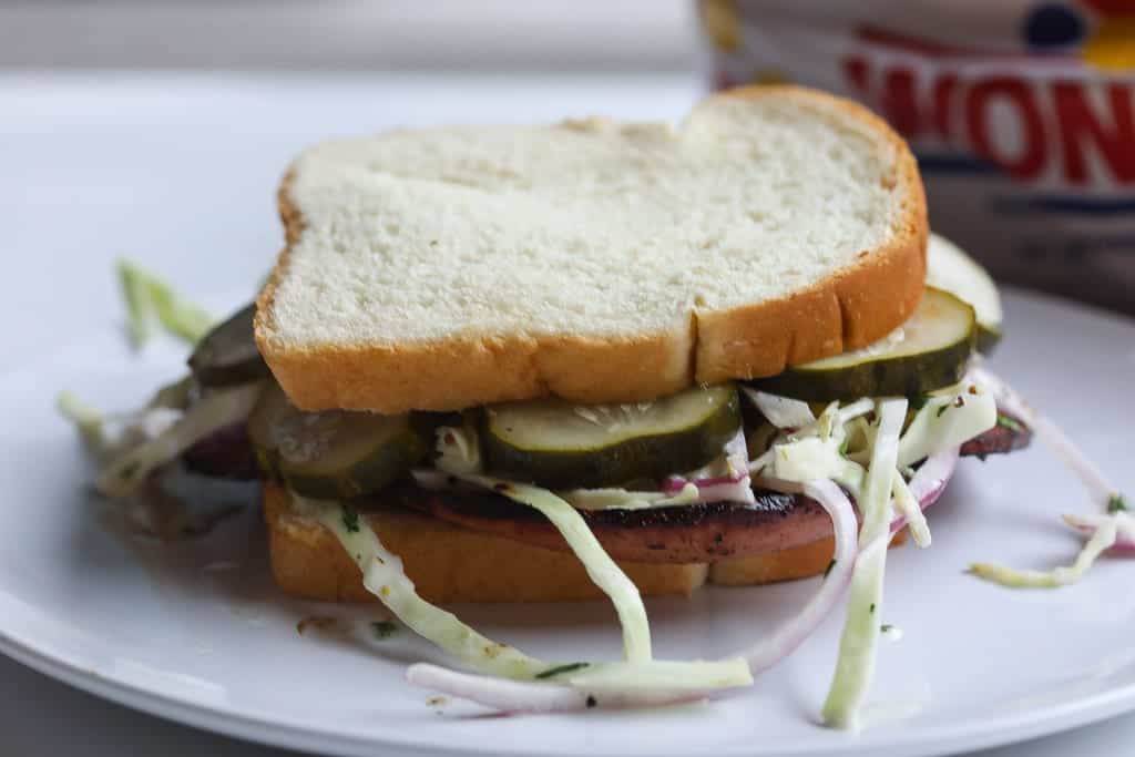 fried bolgna sandwich with slaw on white plate