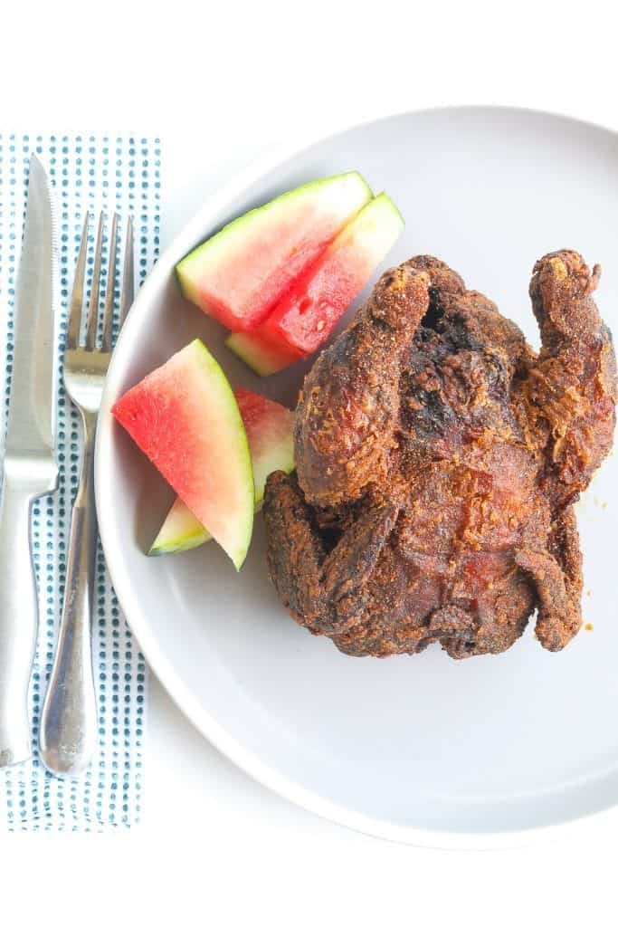 whole deep fried cornish hen on a plate with watermelon