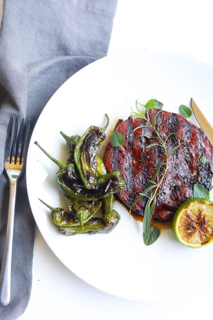 grilled watermelon on a plate with padron peppers and herbs