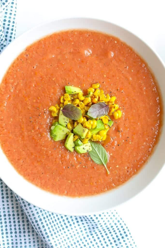 chilled peach gazpacho soup in a bowl topped with corn and avocado