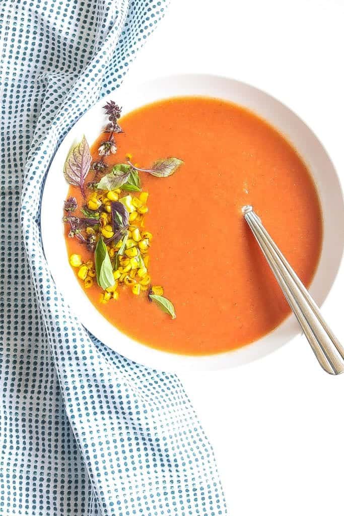 chilled peach gazpacho soup in a bowl topped with corn and avocado