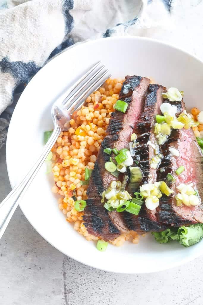 grilled flank steak bowl with couscous and greens