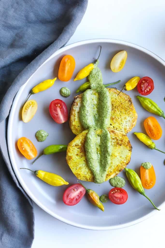 roasted celery steak on a gray plate with tomatoes and peppers