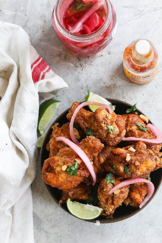 brazilian fried chicken wings (frango a passarinho) in a bowl topped with red onions and cilantro