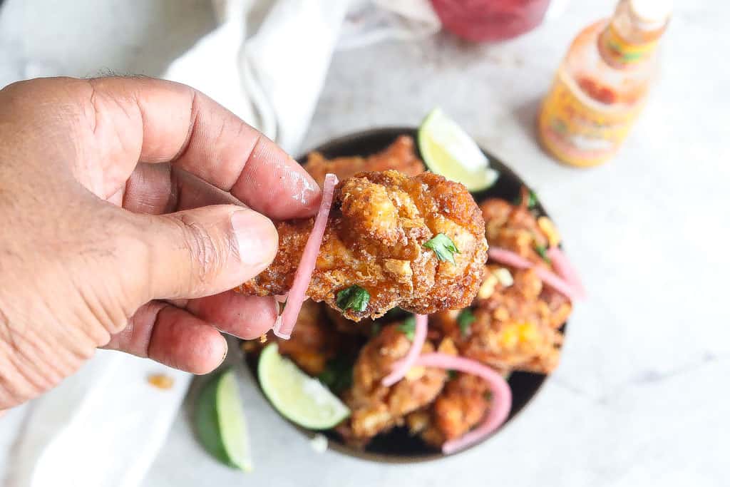 brazilian fried chicken wings (frango a passarinho) in a bowl topped with red onions and cilantro
