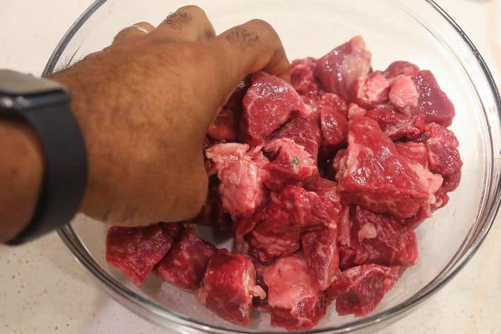 hand massaging beef chunks in lime juice