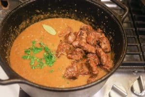 beef and herbs cooking in pot with soup