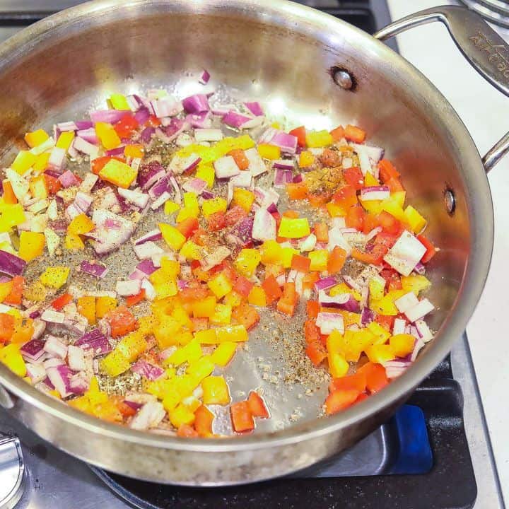 onions, peppers, and garlic sauteing in a skillet