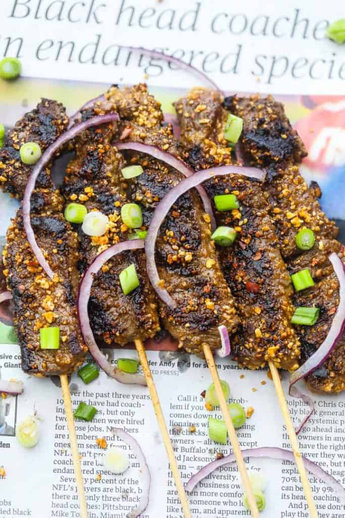 skewers of beef topped with red and green onions as well as suya spice