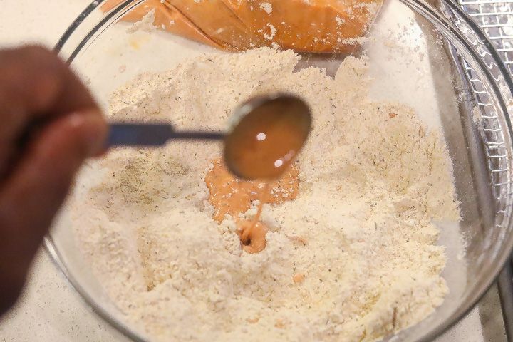 pouring marinade into bowl of flour
