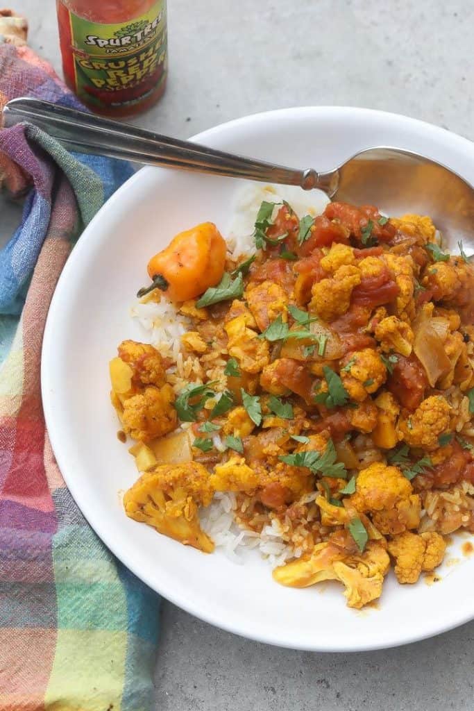 yellow cauliflower florets over rice topped with curry sauce