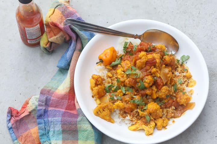 yellow cauliflower florets over rice topped with curry sauce