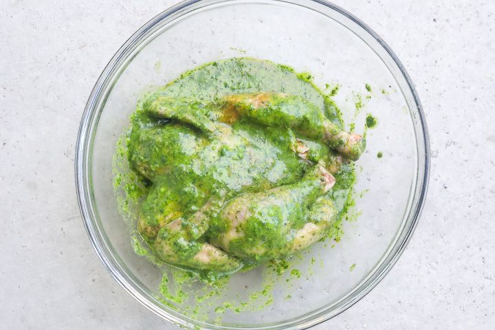 cornish hen marinating in a bowl with green herb mixture