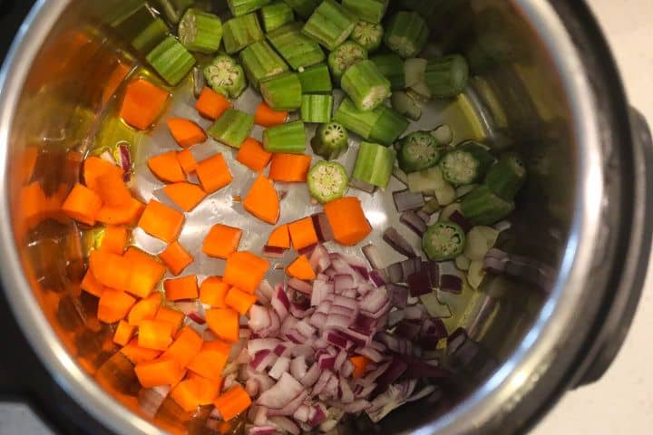 okra, carrots, onions, and garlic sauteing in a pot