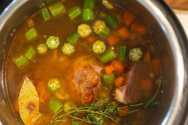 okra, thyme, ham, and carrots boiling in a pot