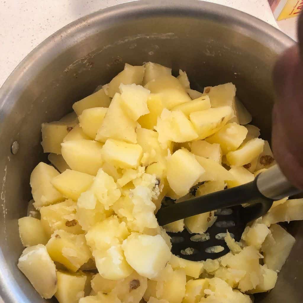 mashing potatoes in a pot