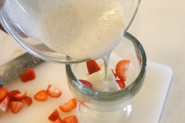 adding crema to strawberries in a glass bowl