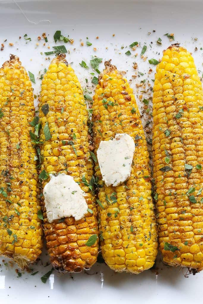 corn on the cob topped with fresh herbs and compound butter