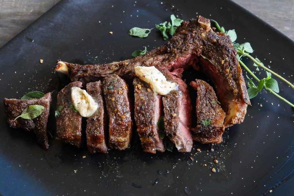 cooked steak on a black plate cut into sliced into slices