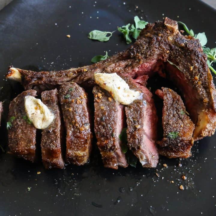 cooked steak on a black plate cut into sliced into slices