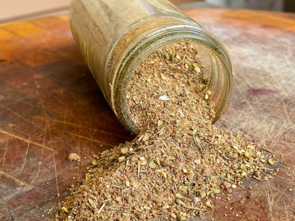 jerk rub ingredients spilling from jar onto cutting board