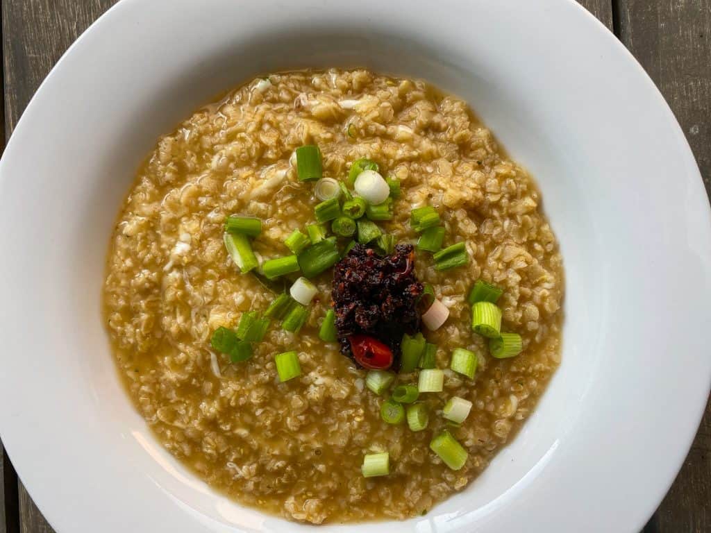 oatmeal in white bowl with green onions and chili paste