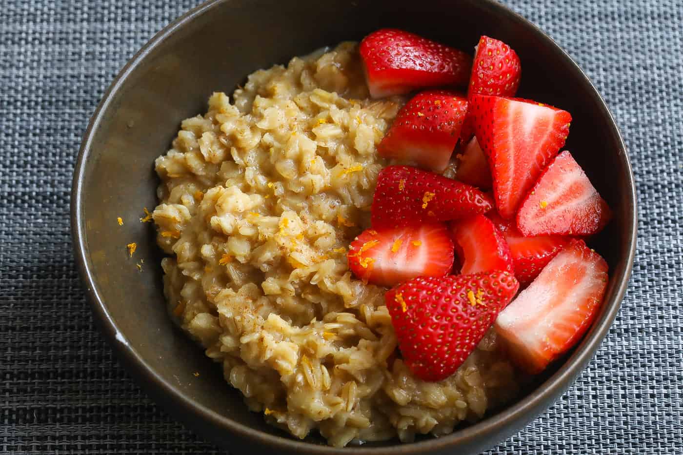 oatmeal topped with strawberries in brown bowl