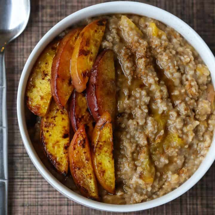 Oatmeal topped with peaches in a white bowl
