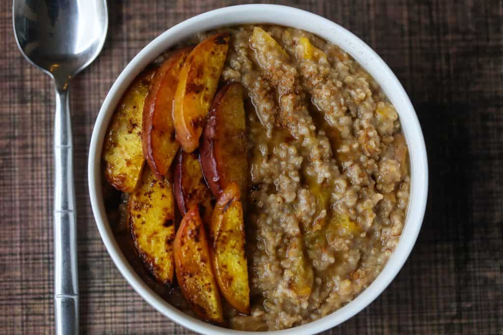 Oatmeal topped with peaches in a white bowl