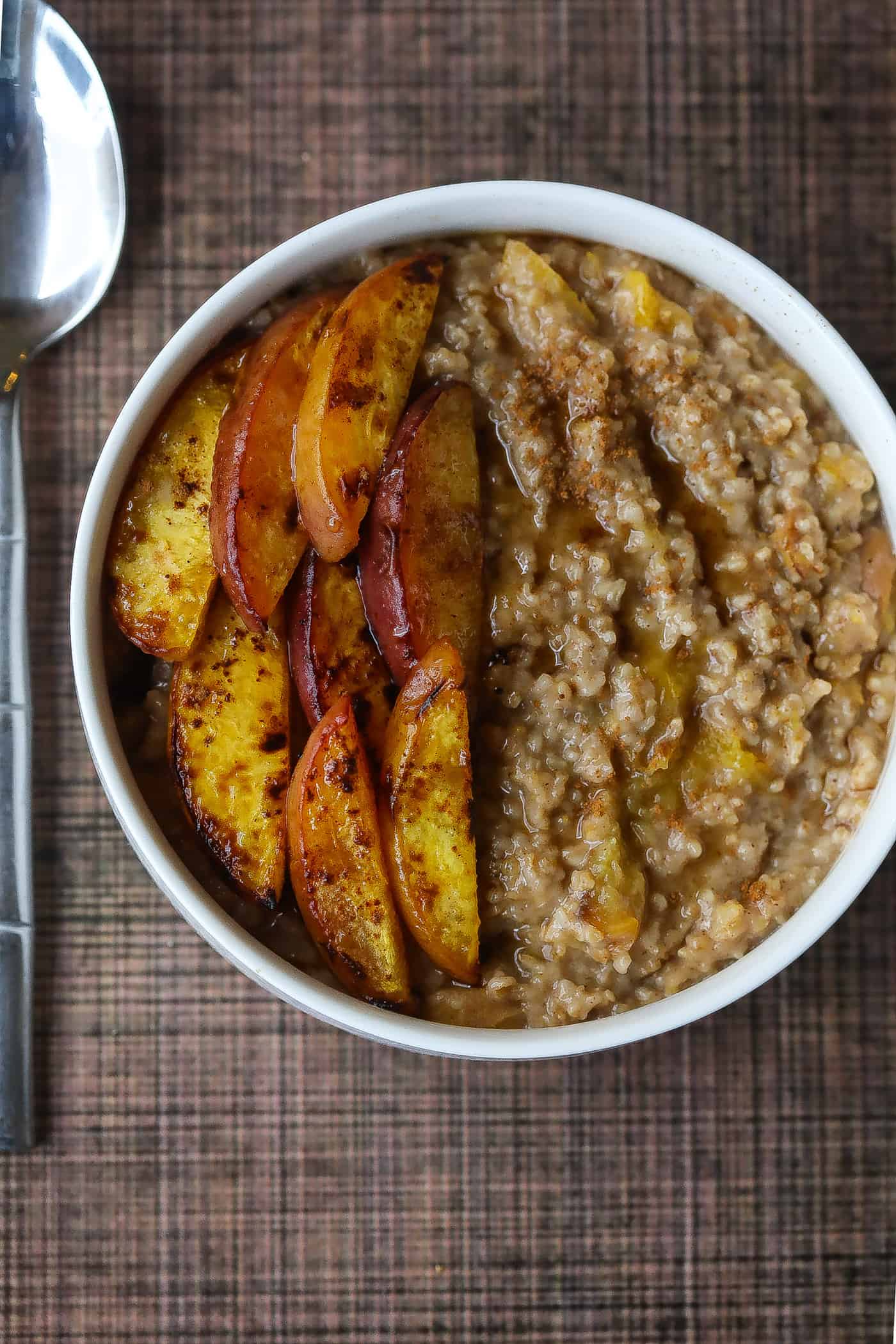 Oatmeal topped with peaches in a white bowl