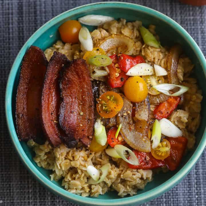 oatmeal topped with bacon and vegetables in a blue bowl