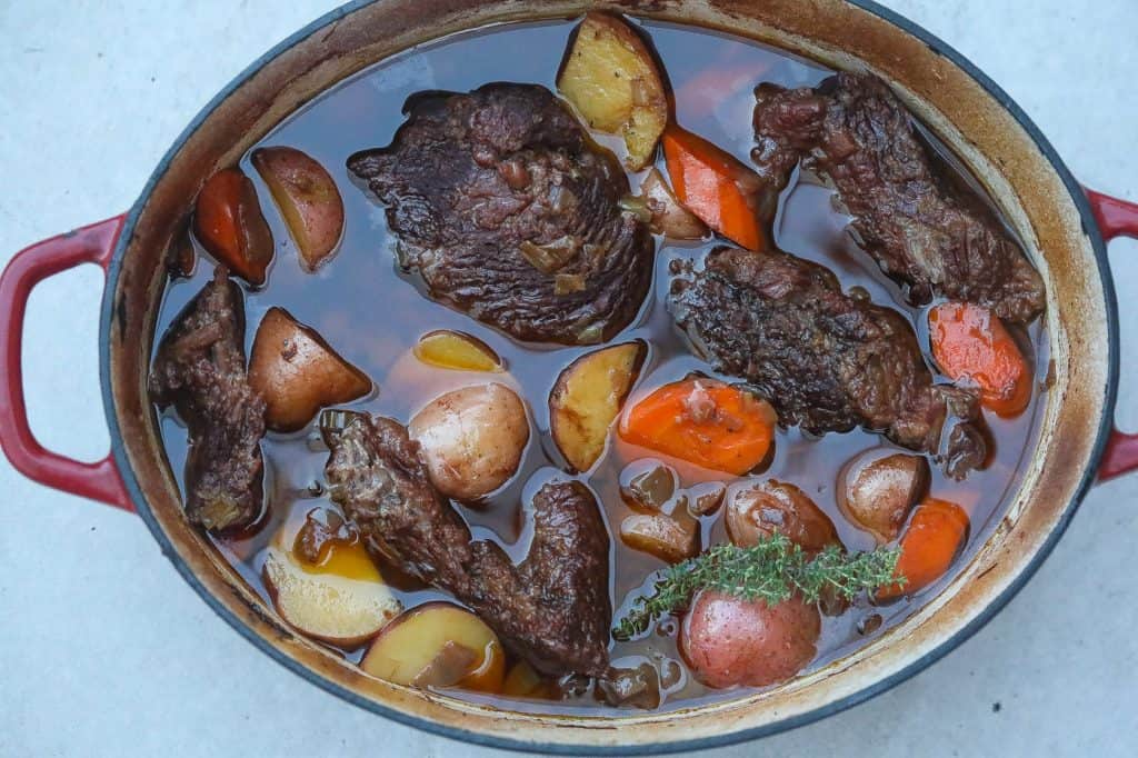 beef pot roast in a dutch oven with carrots and potatoes