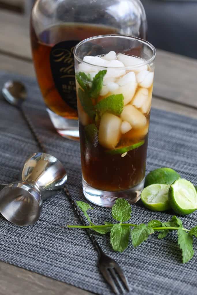 cuba libre cocktail in a tall glass with mint