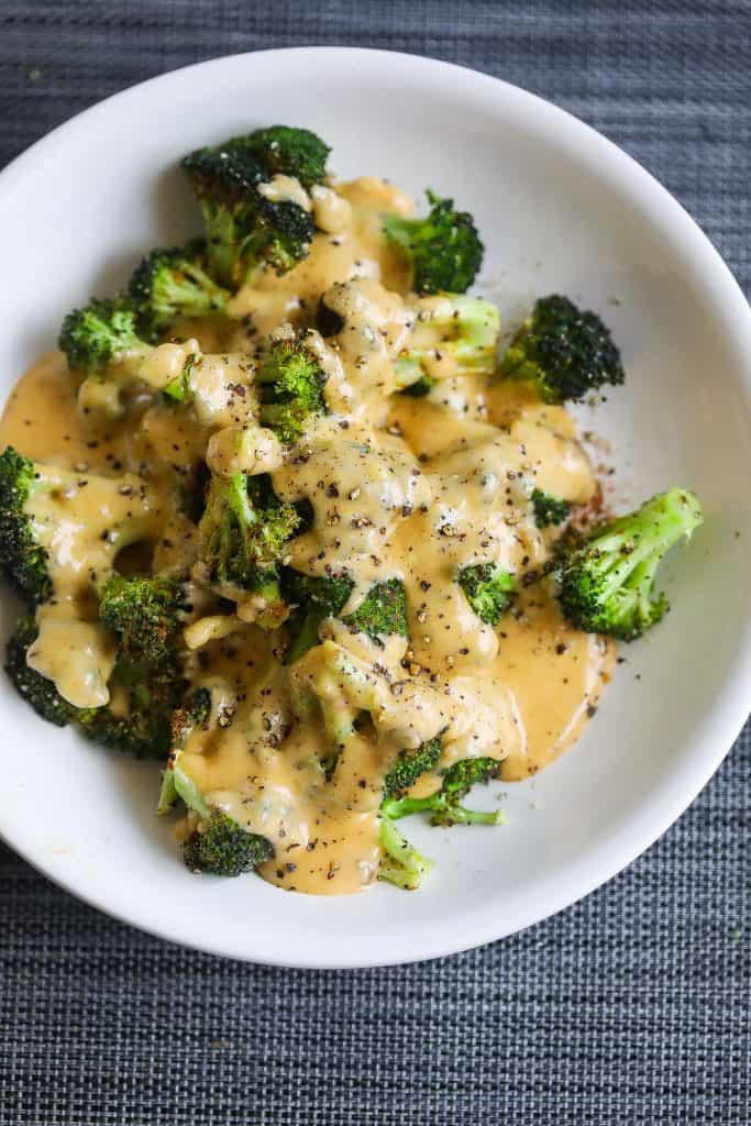 broccoli topped with cheese sauce on white plate