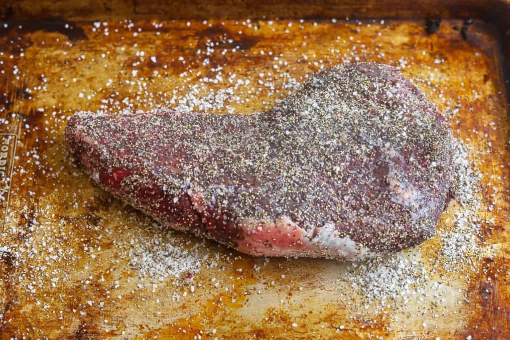 tri tip steak seasoned with salt and pepper on a platter